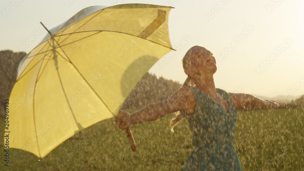 特写：无忧无虑的年轻金发女人让春雨落在她身上。