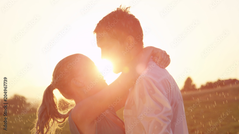 CLOSE UP: Easygoing young couple kisses in the rain on a picturesque evening.