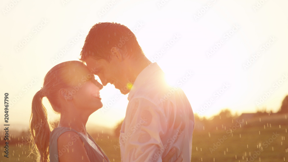 LENS FLARE Man gazes affectionately into womans eyes while they dance in rain