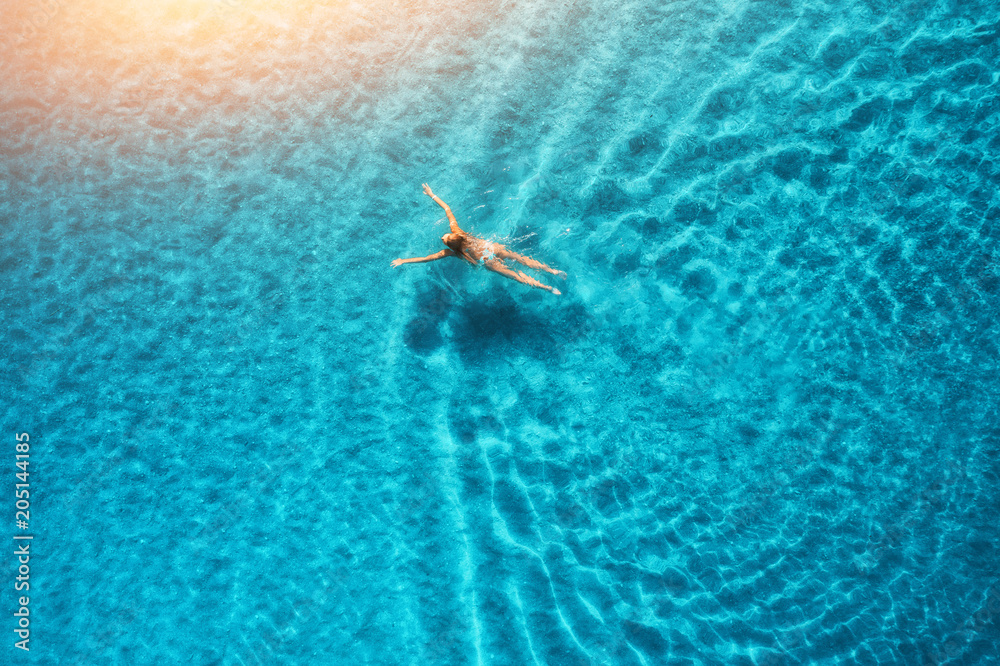 马尔代夫日落时游泳女子的鸟瞰图。地中海。年轻g的空中海景