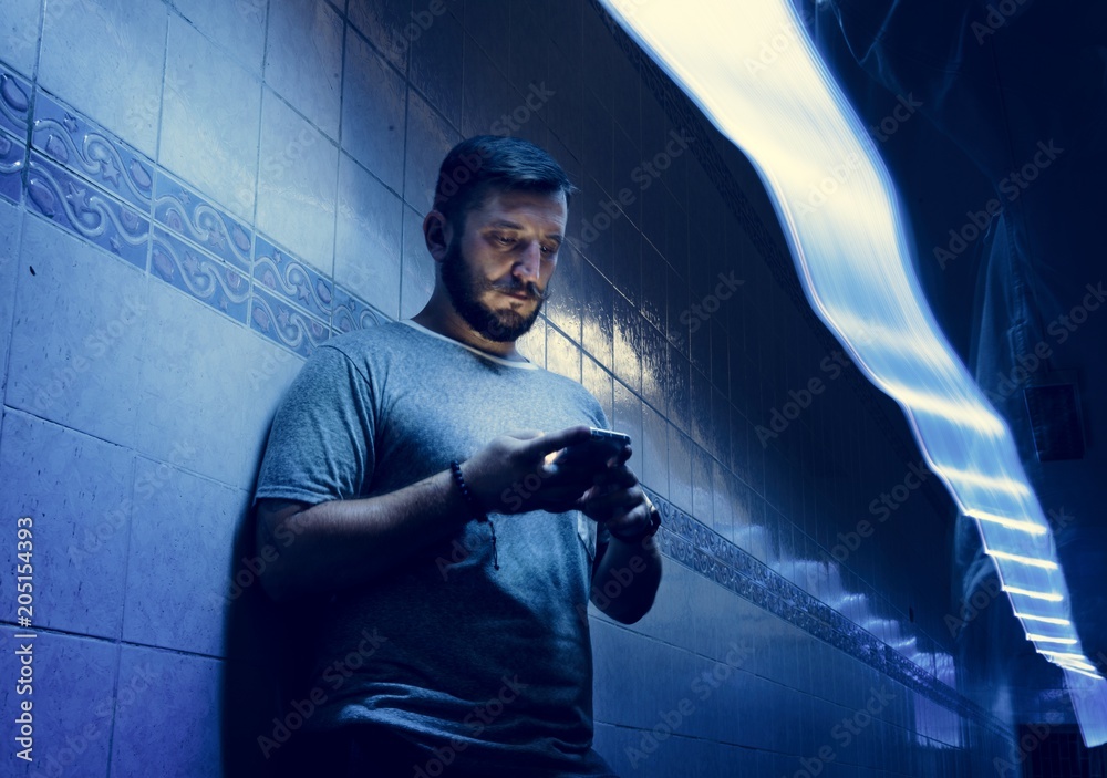 Closeup of a man using mobile phone in the dark with long exposure light