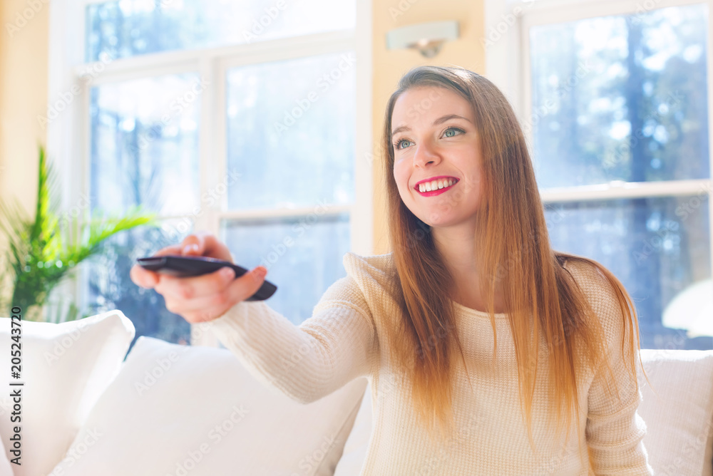 Young woman watching with remote control watching TV in the living room