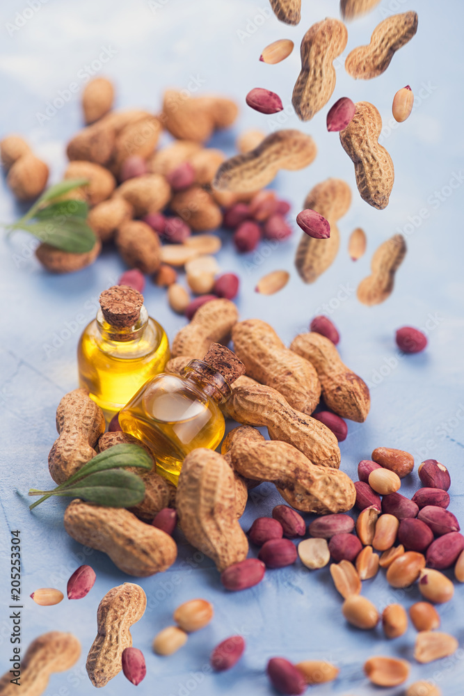 Natural peanuts with oil in a glass jar on the blue concrete background