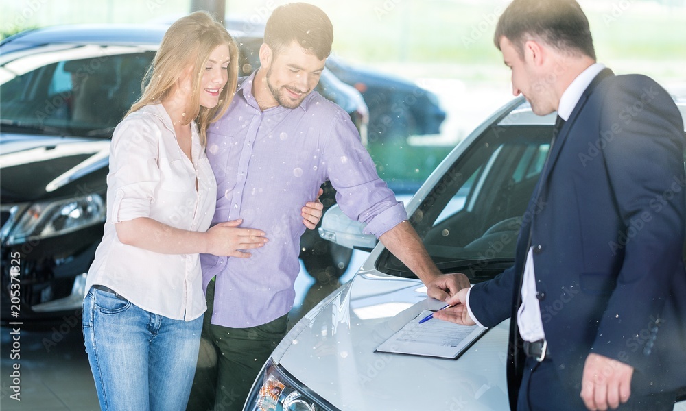 Happy couple with car dealer