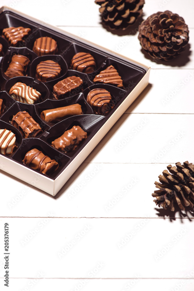 A lot of variety chocolates in box on white wooden background