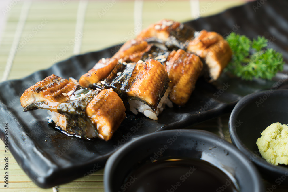 黑盘子里的Unagi寿司，配上日本酱汁和绿叶装饰，日本食物，关闭