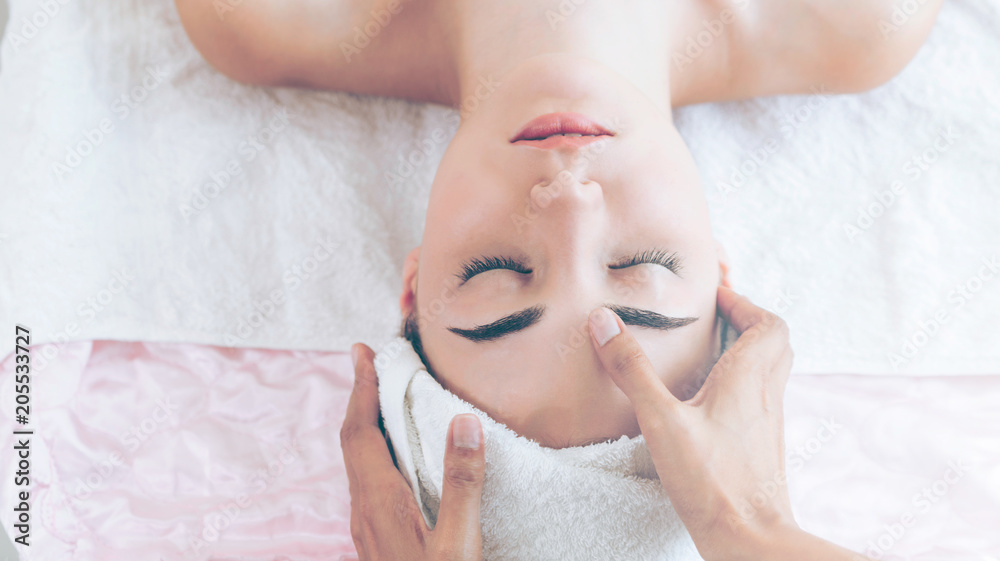 Woman gets facial and head massage in luxury spa.