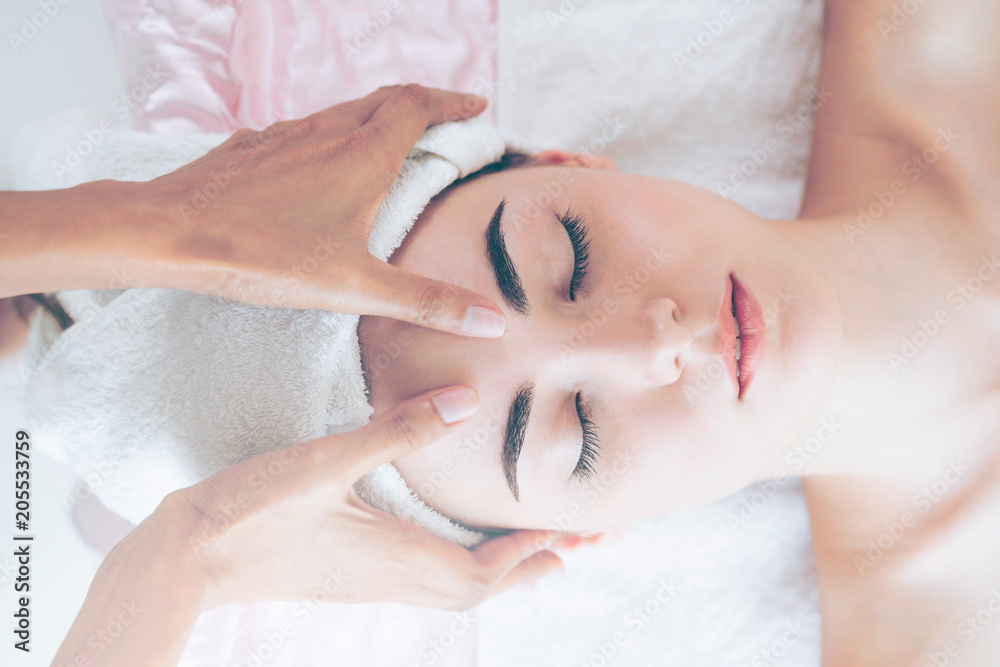 Woman gets facial and head massage in luxury spa.