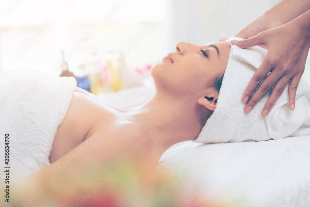 Relaxed young woman lying on spa bed for massage.