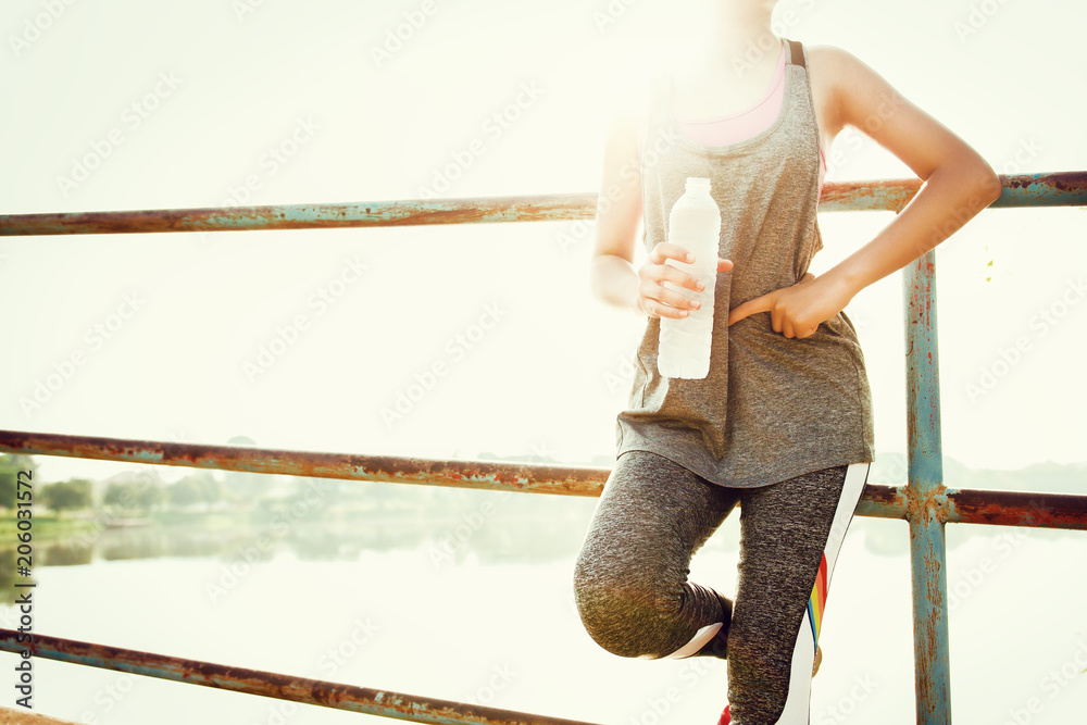 sport woman standing after running with hand holding water bottle at park