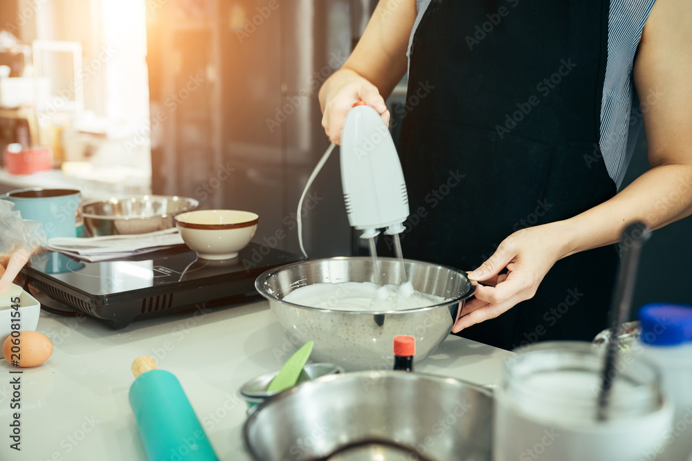 一位女士在周末聚会上用奶油混合物为家人做生日蛋糕。