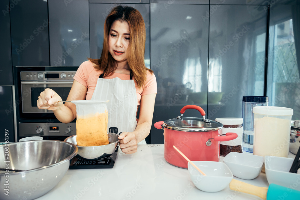 亚洲女性正在过滤制作茶霜，用于周末生日派对的杯蛋糕浇头