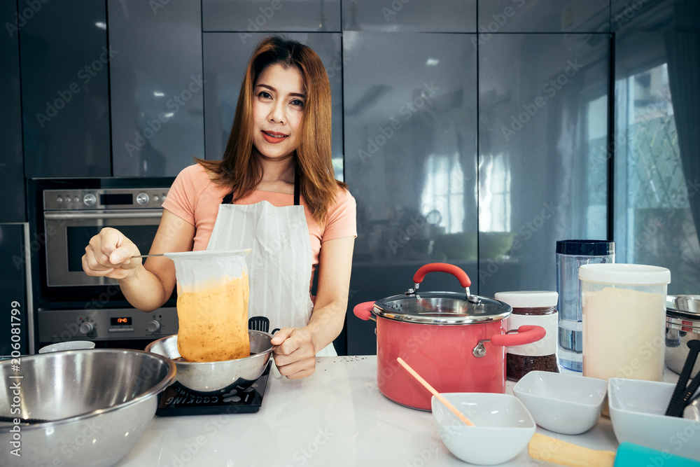 亚洲女性正在过滤，以制作周末生日派对杯蛋糕的茶奶油