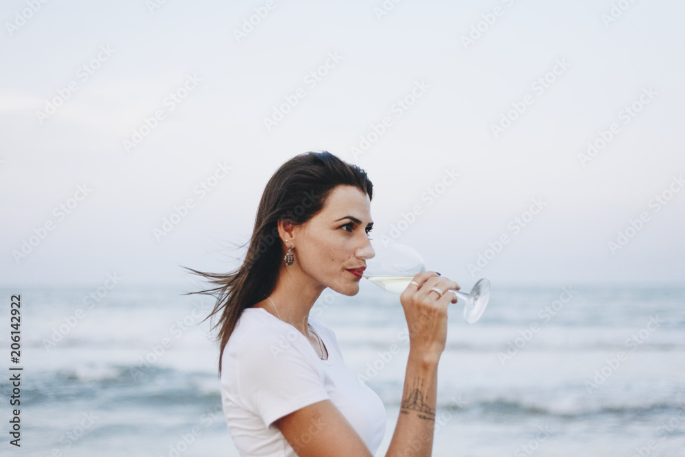 在海滩边喝一杯葡萄酒的女人