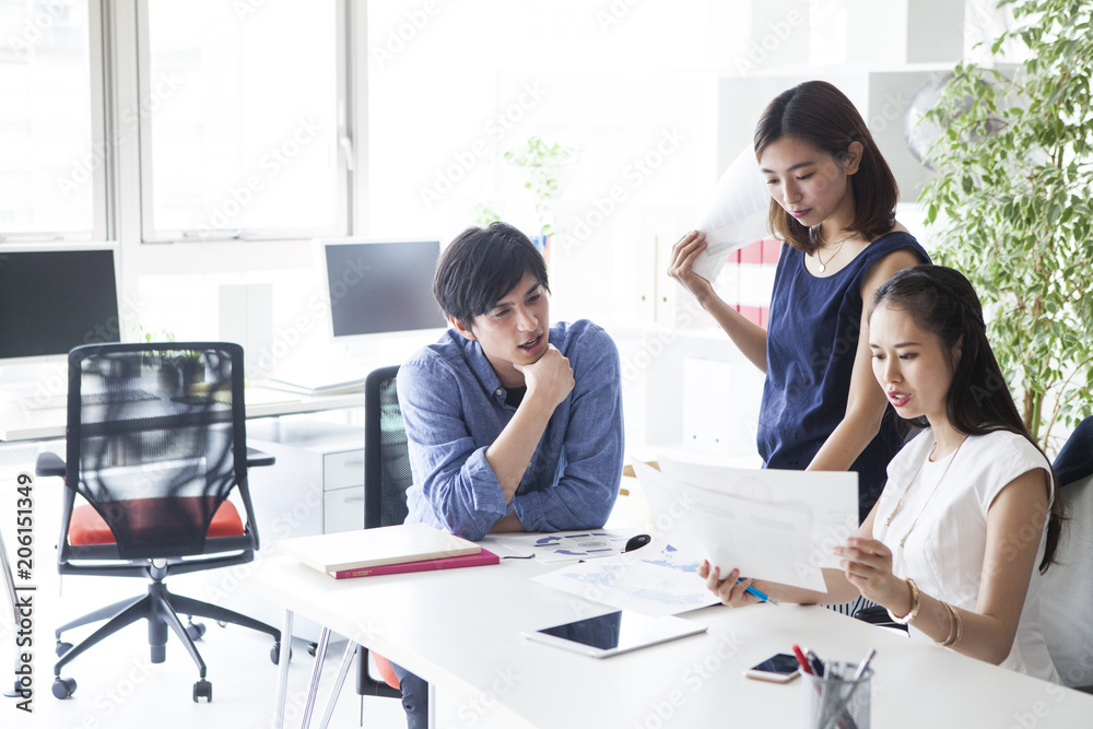 三人の会社員たちは資料見ながら会議をしている