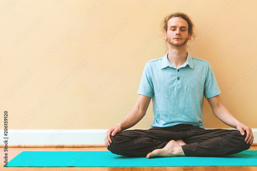 Man in a meditation pose inside a big bright room