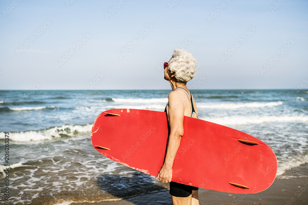 拿着冲浪板的老年妇女