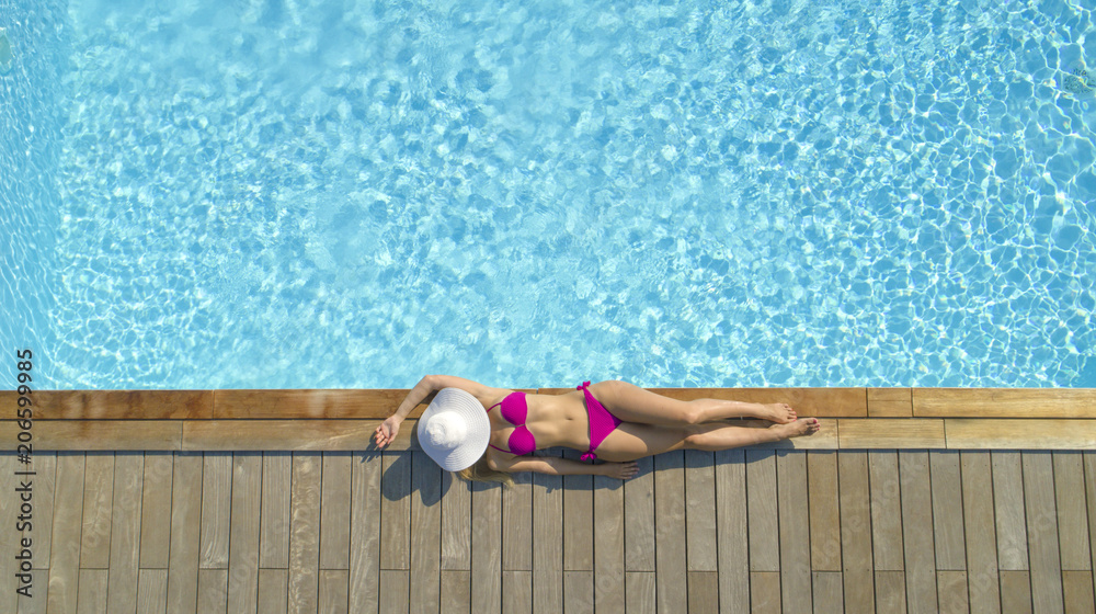 空中飞航：热带夏季穿着粉色比基尼晒日光浴的迷人女性游客。