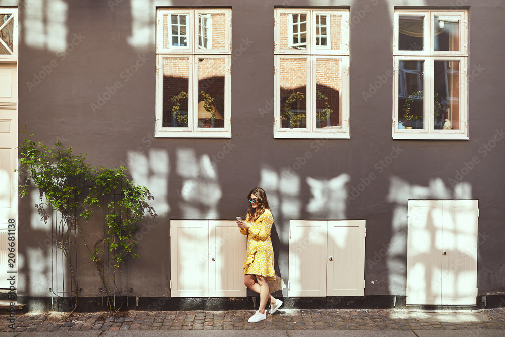 Young woman leaning against a city wall using her cellphone