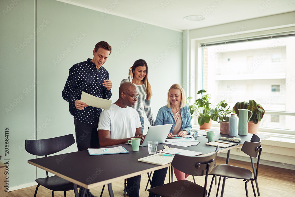 Smiling colleagues working online together in a modern office