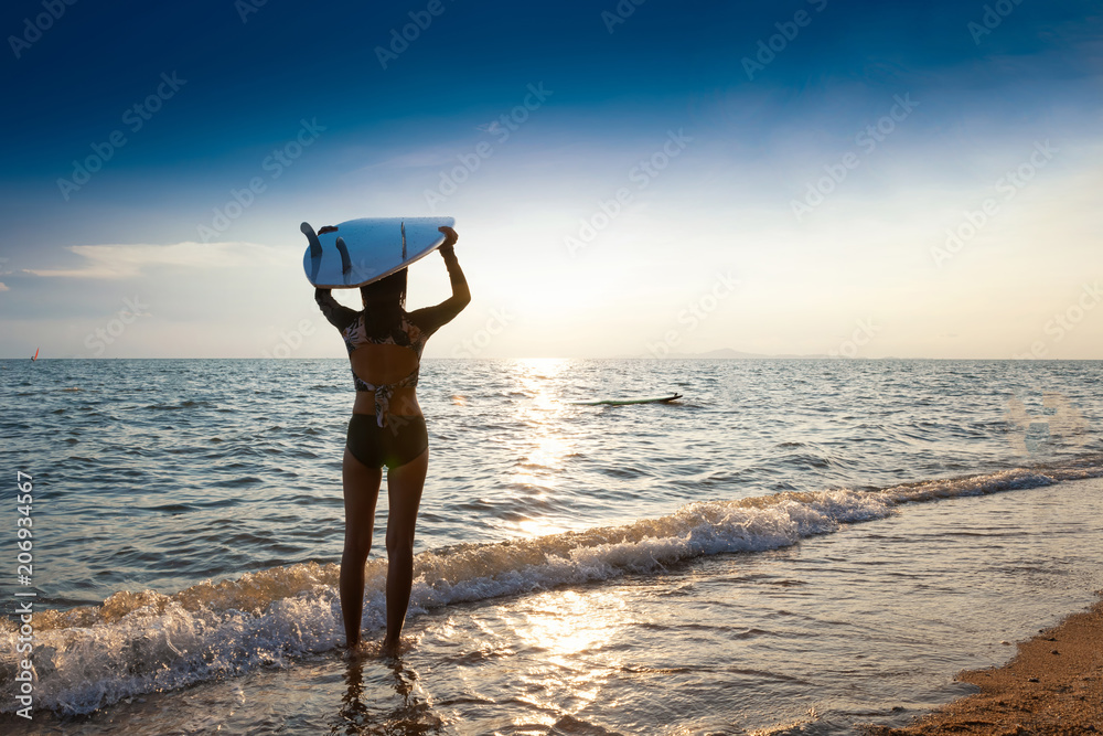 一名冲浪者拿着冲浪板在沙丘上眺望海浪