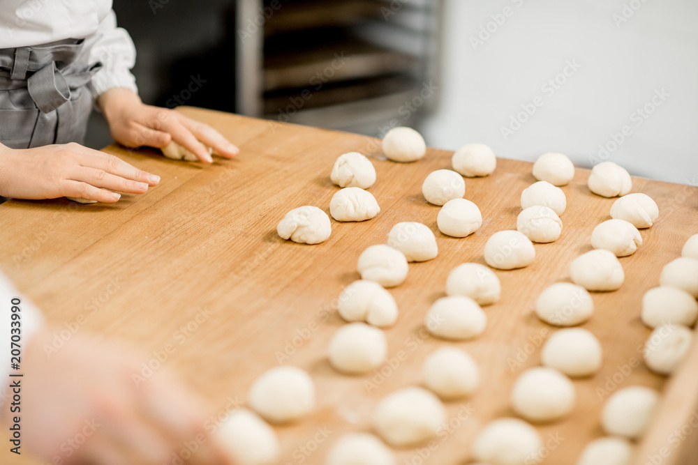 Forming daugh balls for baking buns on the wooden table at the manufacturing