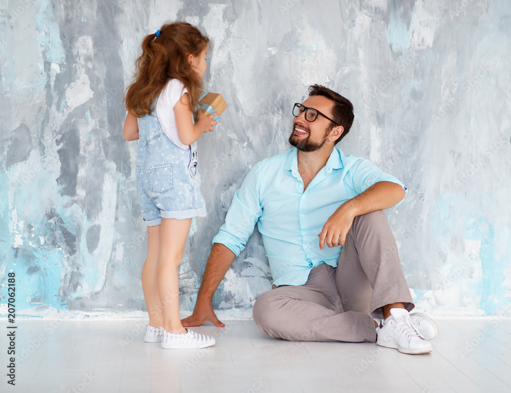 Fathers day. Happy family daughter hugging dad and laughs near an wall.