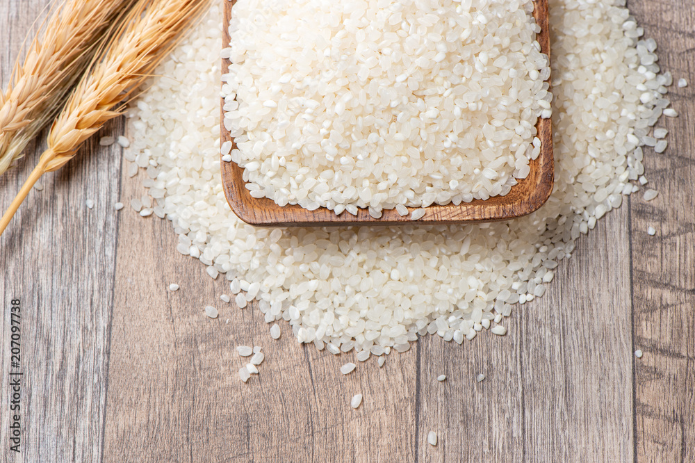 raw rice in a wooden bowl on wooden background