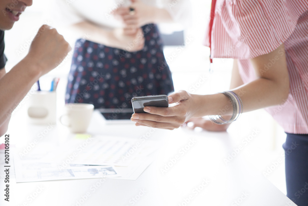 オフィスでスマートフォンを見ながら会議