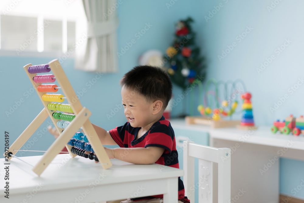 亚洲幼童学会数数。可爱的孩子在玩算盘玩具。小男孩玩得很开心