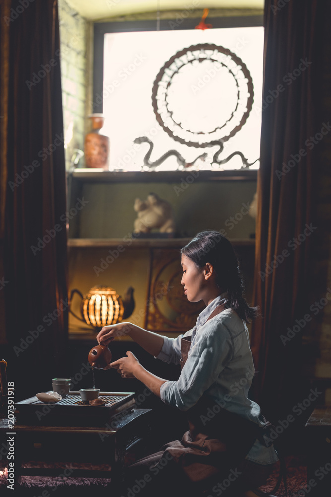 Young woman pouring tea from a teapot