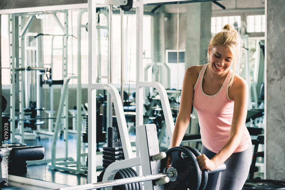 Woman doing and lifting dumbbell for weight training at sport gym with happy and smile, gym workout 