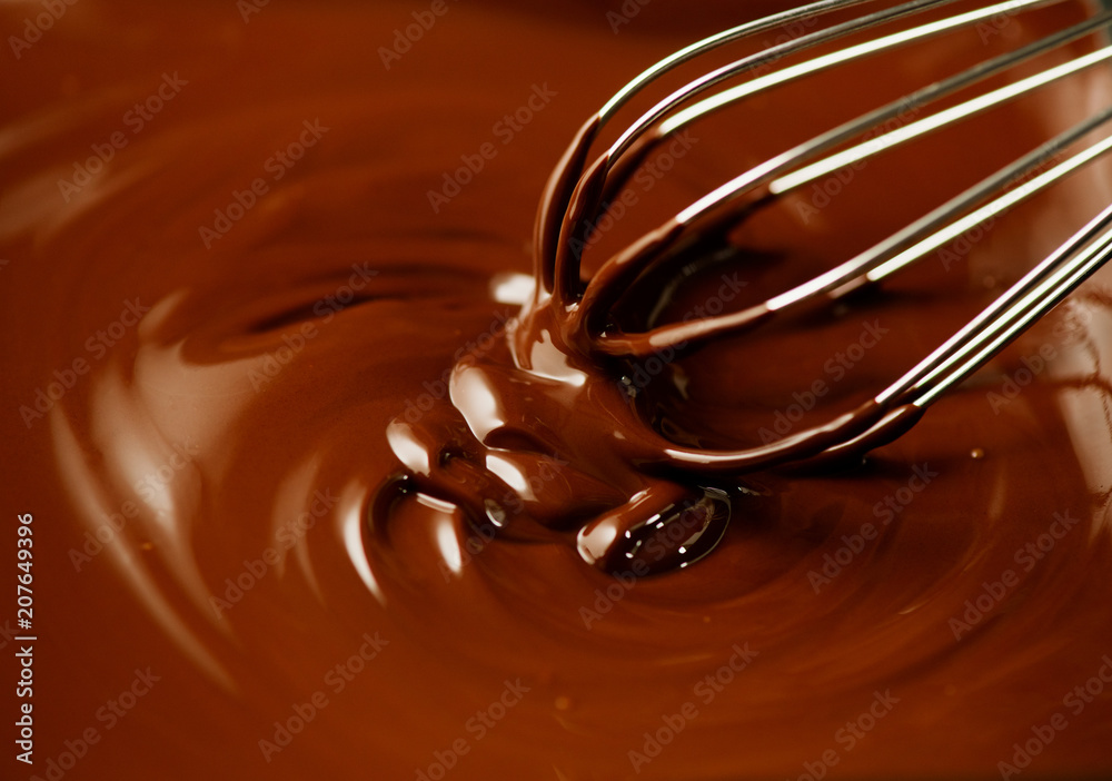 Chocolate. Mixing melted dark chocolate with a whisk. Closeup of liquid hot chocolate swirl. Confect