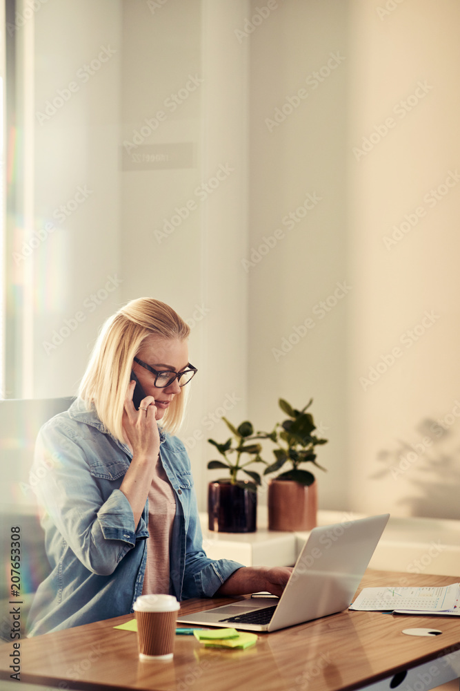 专注的年轻女商人在办公室里用手机聊天