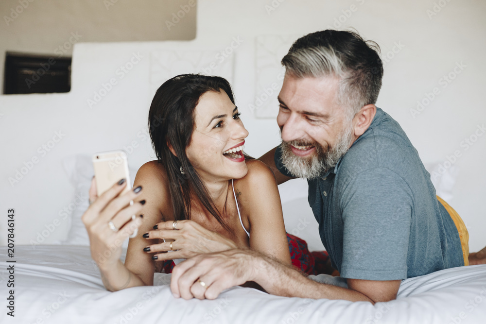 Couple using a smartphone in bed