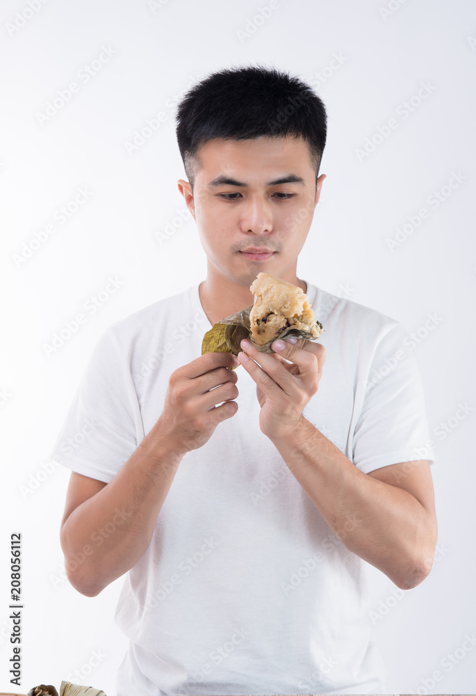 A man is eating delicious zongzi(rice dumpling) and feel delicious on Dragon Boat Festival, Asian tr