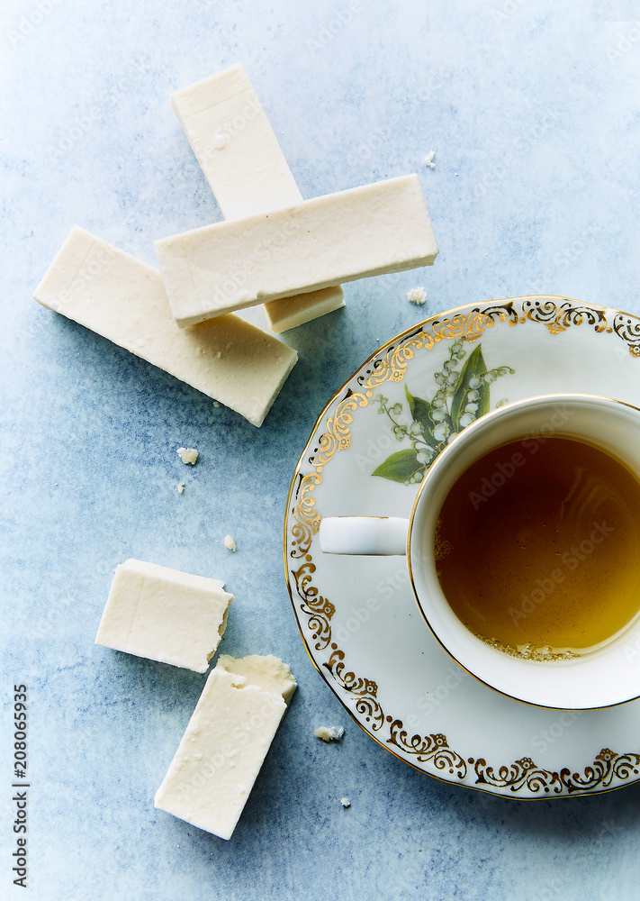 A cup of tea and pastilles on a blue background.