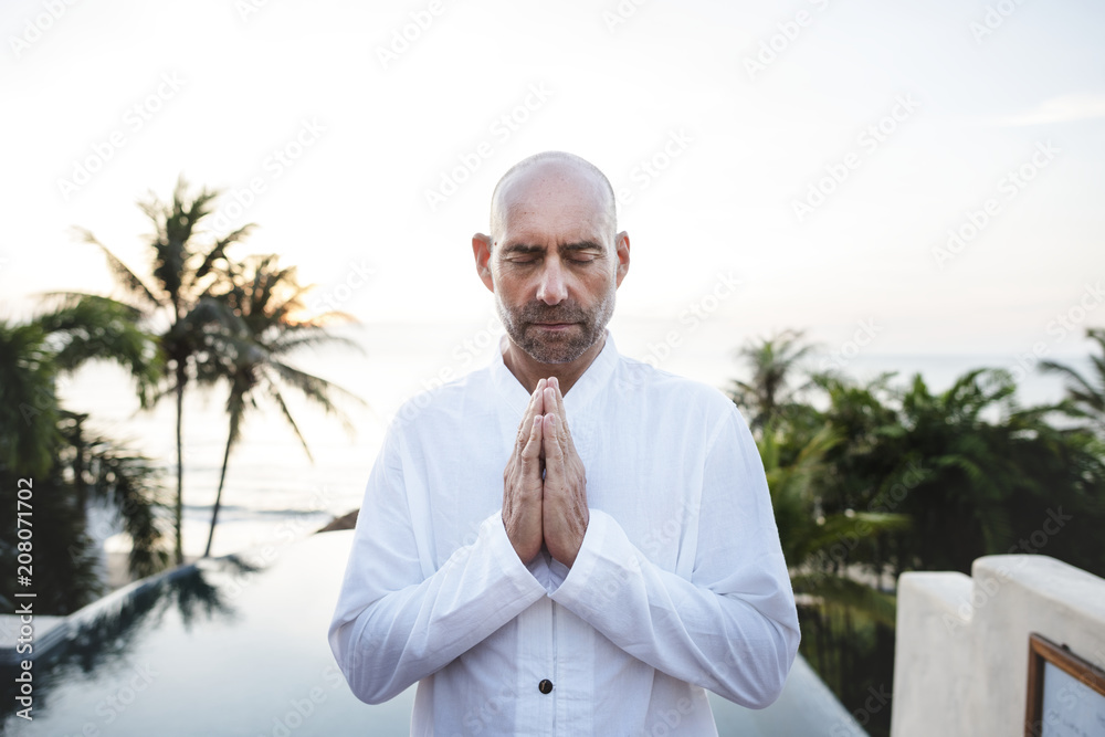 Senior adult practicing yoga by the pool