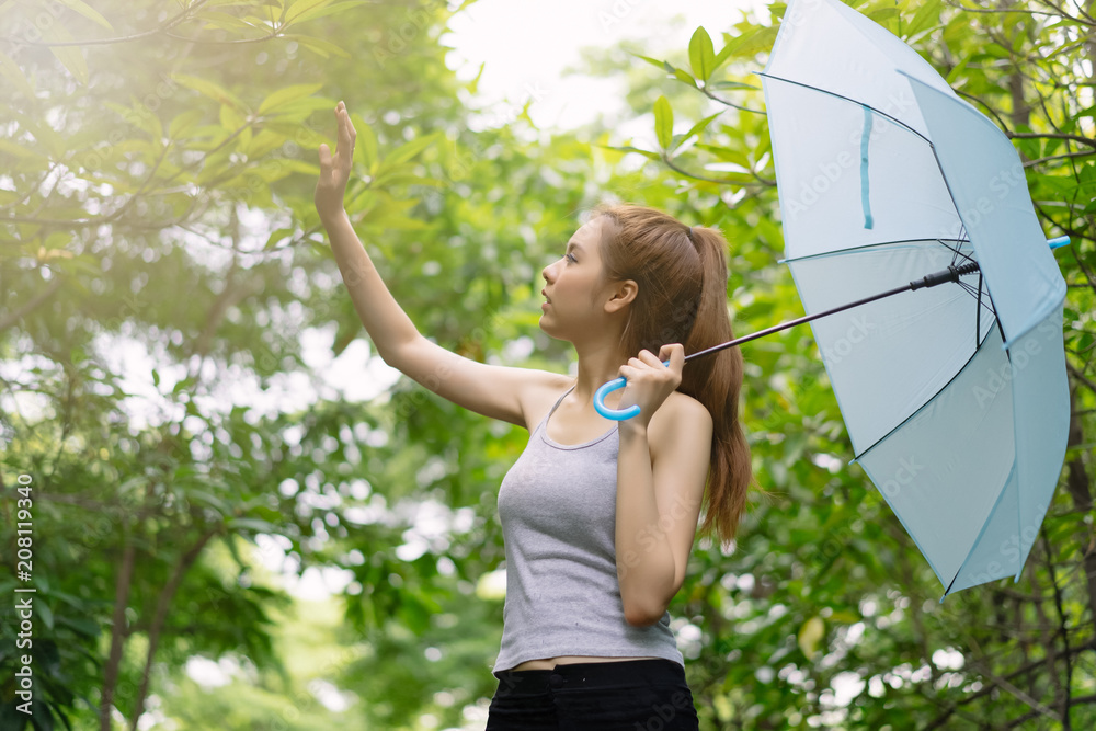 一个美丽的年轻亚洲侧视图，在雨中打着伞在花园里玩耍