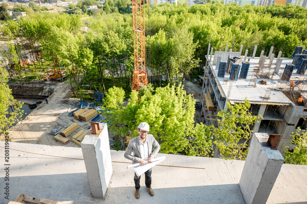 绿化区住宅建筑施工现场俯视图，工程师站立