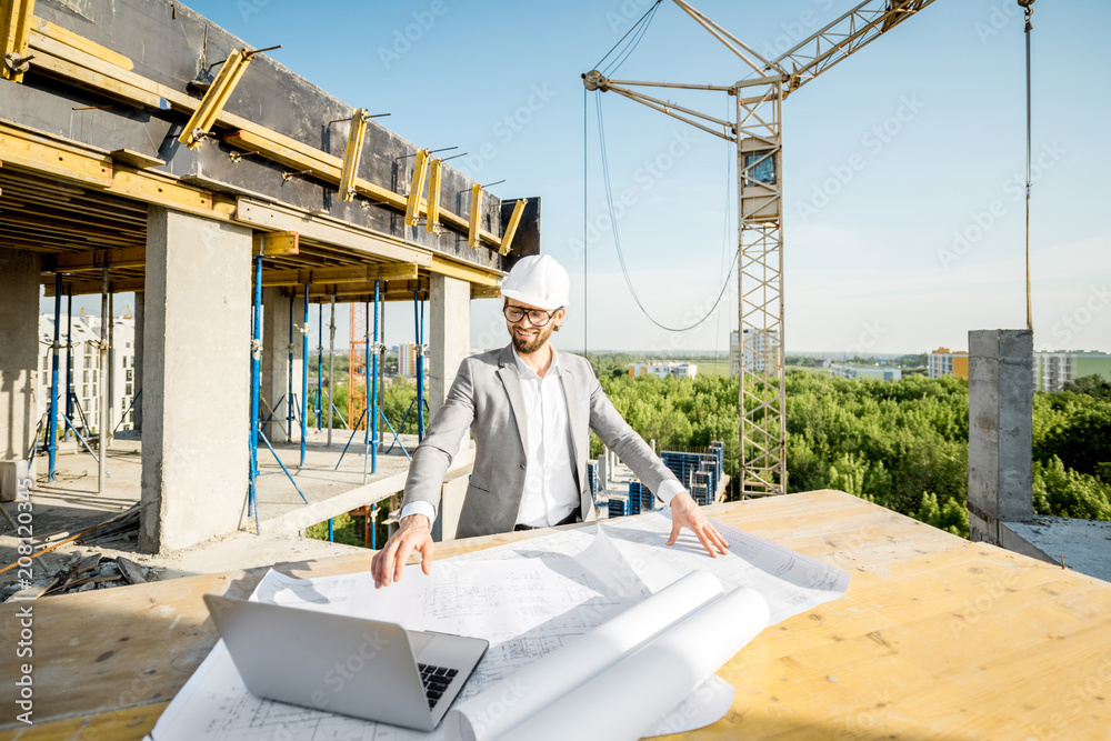 英俊的工程师在户外施工现场的桌子上处理建筑图纸