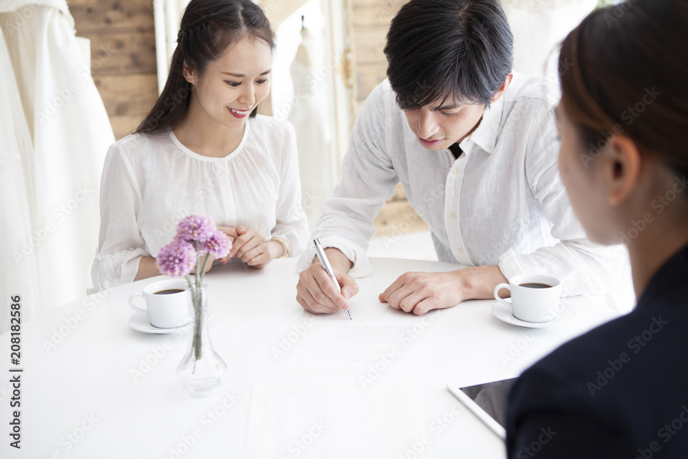 プランナーと話し契約書にサインする新婚夫婦