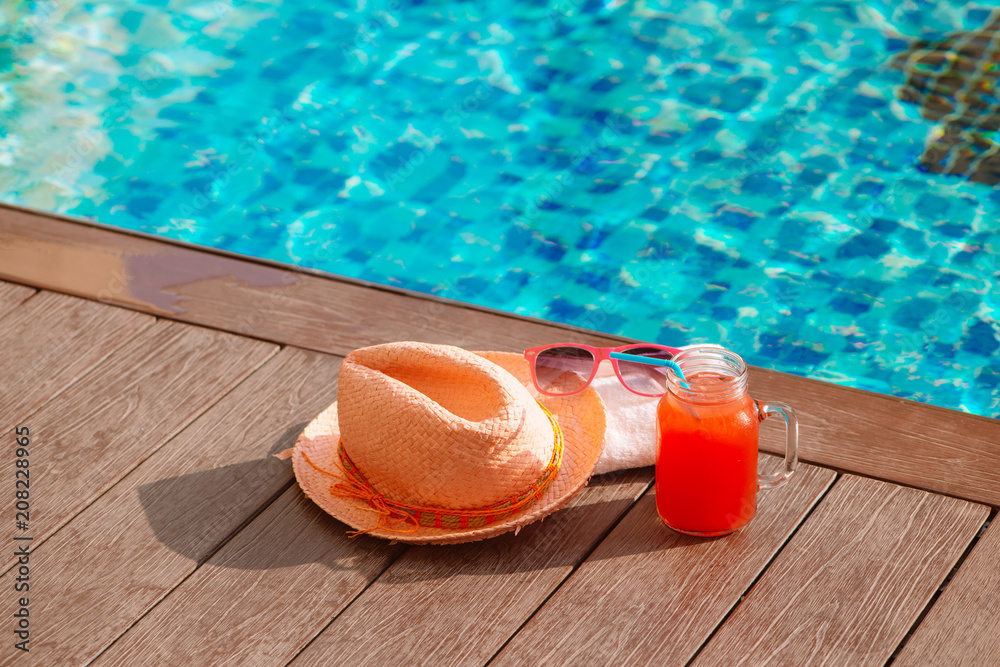 Water-melon fresh fruit smoothie drink with sunglasses and straw hat on swimming pool border - holid