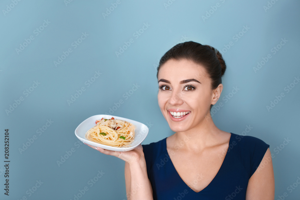 Young woman with plate of tasty pasta on color background