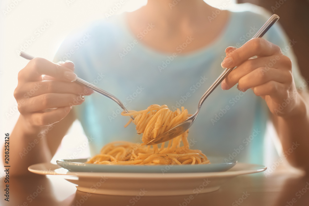 Young woman eating tasty pasta at table, closeup