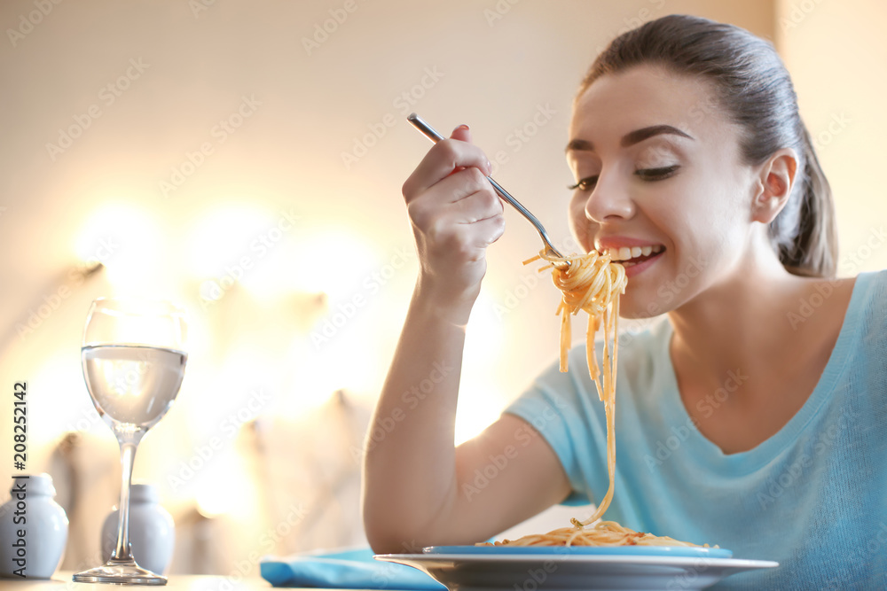 年轻女子在咖啡馆吃美味的意大利面