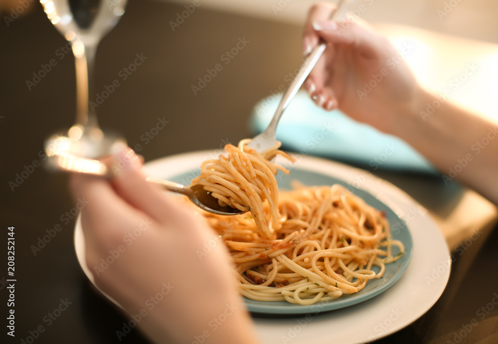 年轻女子在餐桌上吃美味的意大利面，特写镜头