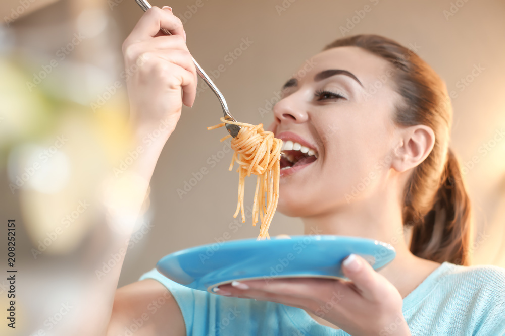 Young woman eating tasty pasta in cafe