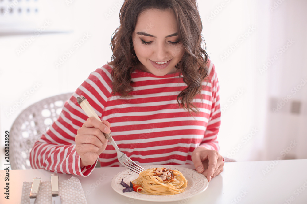 年轻女人在餐桌上吃美味的意大利面