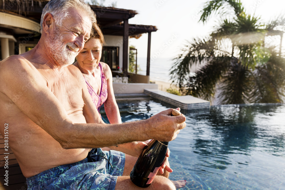 Senior couple opening a champagne bottle